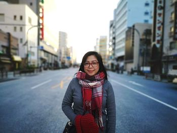 Portrait of smiling young woman standing on road in city