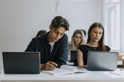 Multiracial male and female teenage students studying at desk in classroom