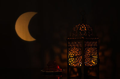 Lantern and small plate of dates fruit with moon shape from light for holy month of ramadan kareem.