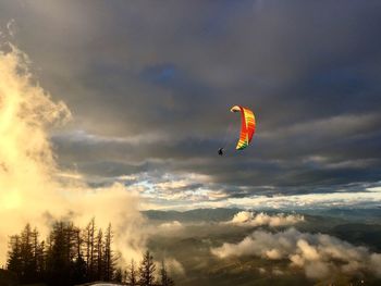 Low angle view of person paragliding against sky during sunset