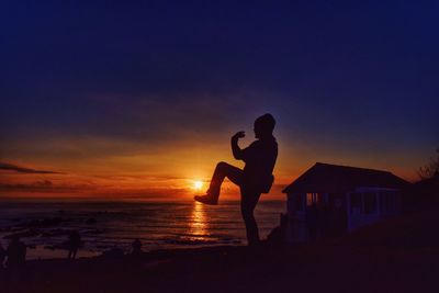 Silhouette men on beach against sky during sunset