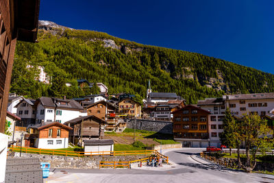 Houses by road against clear blue sky in city