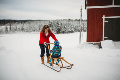 Grandma on old antique sleigh with grandchild in farm in norway