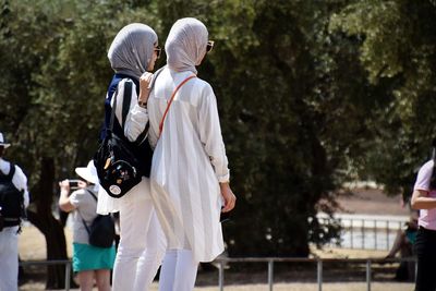 Female friends standing against trees