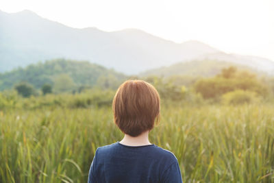 Rear view of woman standing on field against mountains