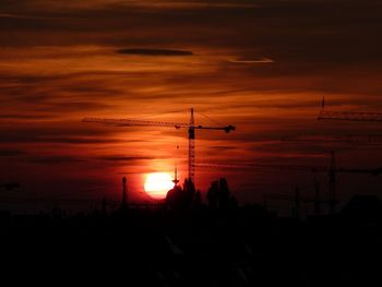 Silhouette of city against dramatic sky during sunset