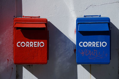 Two mailboxes on a wall, red and blue 