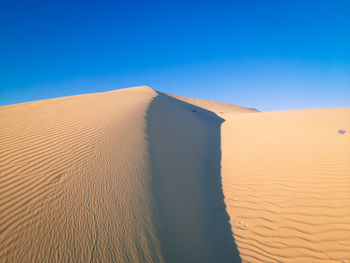 Scenic view of desert against clear blue sky