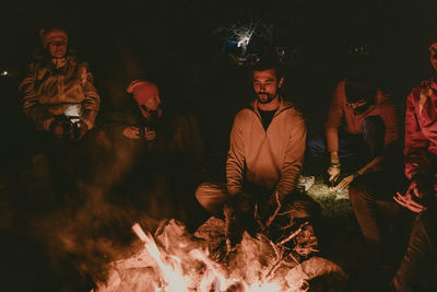 People sitting by fire at night