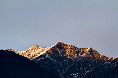 Low angle view of snowcapped mountains against clear sky