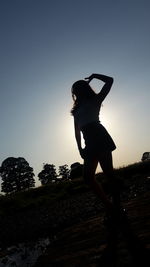 Silhouette woman standing against clear sky during sunset