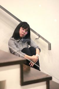 Portrait of young woman sitting on wall