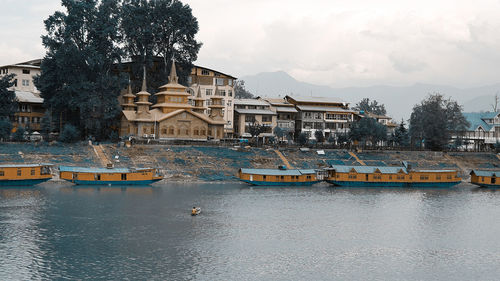 Scenic view of river by buildings against sky