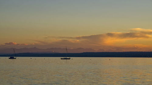 Silhouette sailboats in sea against sky during sunset