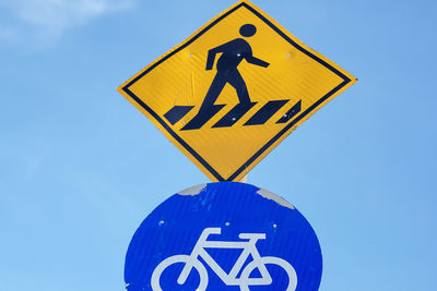 Low angle view of road sign against blue sky