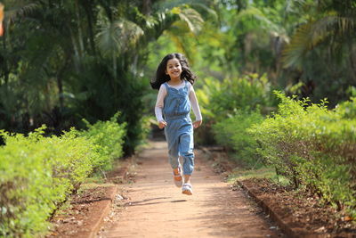 Full length of girl running on footpath at park