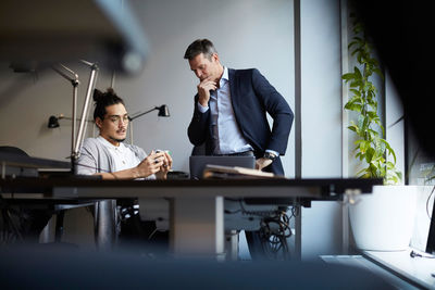 Entrepreneur explaining solar toy car to male bank manager in creative office