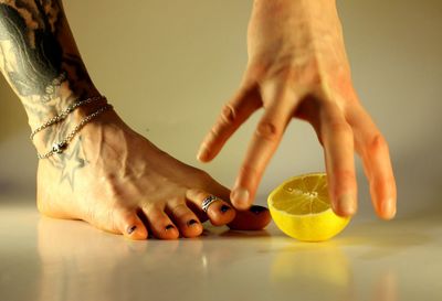 Low section of woman's bare foot and hand with lemon