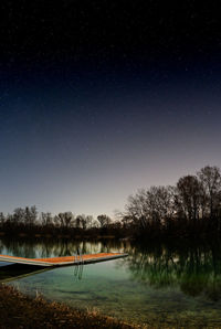 Scenic view of lake against clear sky at night