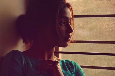 Portrait of young woman looking away against wall