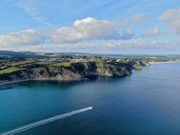 Scenic view of sea at cornwall coastline with cliffs and powerboat 