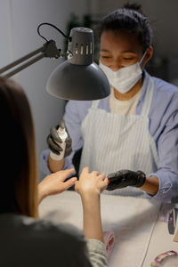 African american woman gets a manicure in a beauty studio. body hair and nails care