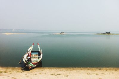 Boat moored on sea against clear sky