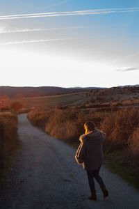 Rear view of man walking on road