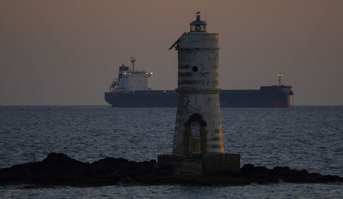 Lighthouse by sea against sky