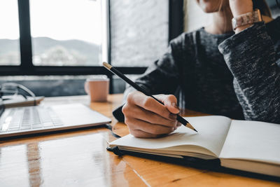 Midsection of man reading book on table