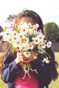 Close-up of girl covering face with bouquet of flowers