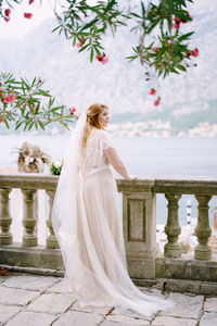 Rear view of woman standing against white wall