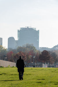 Rear view of man standing on field against sky
