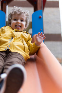 Portrait of smiling boy sitting on yellow outdoors