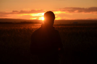 Silhouette man on field against sky during sunset