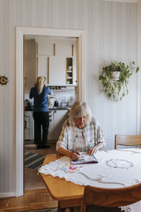 Senior woman solving puzzle while sitting on dining table at home