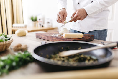 Chef preparing stuffing for ravioli, grating parmesan cheese