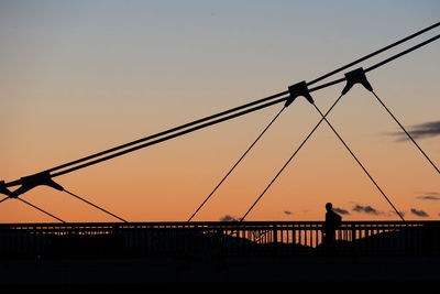 Silhouette suspension bridge against sky during sunset