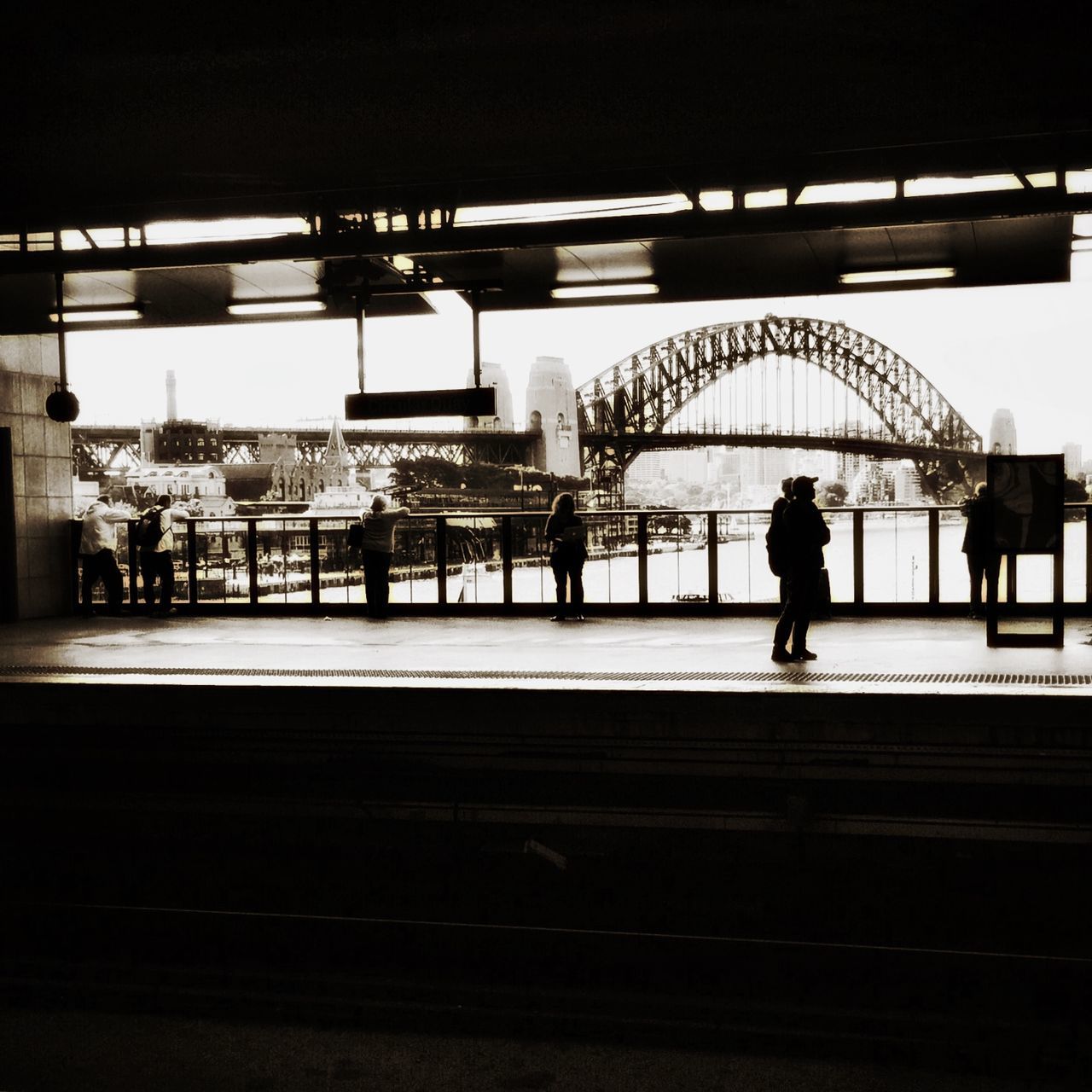 railroad station, transportation, railroad station platform, architecture, built structure, indoors, public transportation, rail transportation, railroad track, men, walking, silhouette, incidental people, travel, railing, illuminated, mode of transport, person, passenger