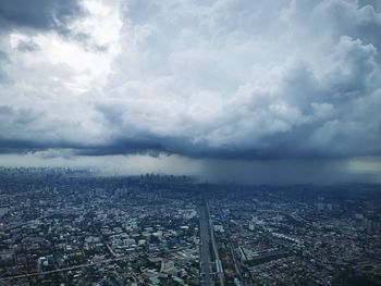 Aerial view of cityscape against cloudy sky