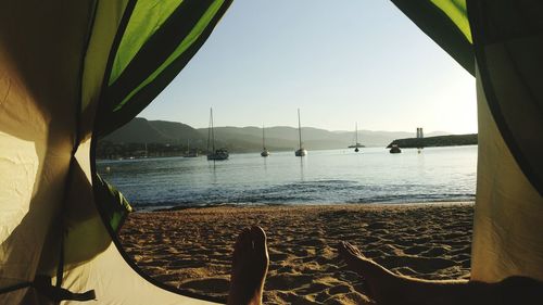 Low section of man on beach against clear sky