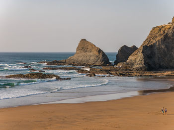 Rocks on beach against clear sky