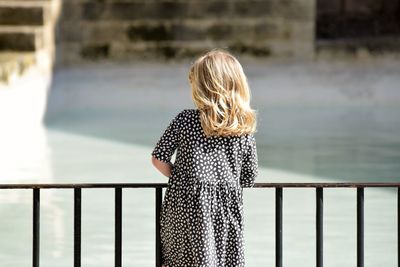 Rear view of woman standing against railing