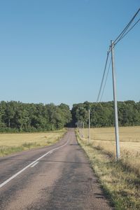 Road amidst field against clear sky