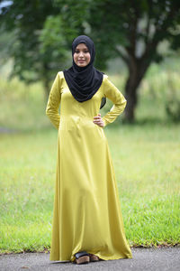 Portrait of smiling young woman standing on field