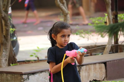 Cute girl holding toy while looking away