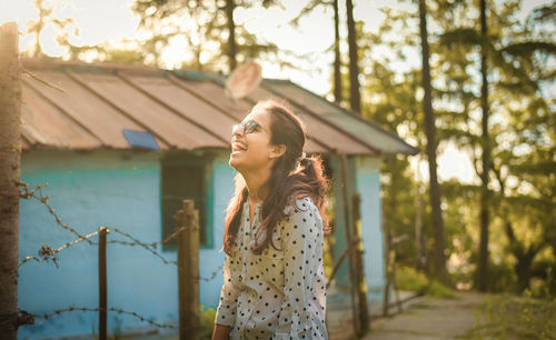 Woman laughing while standing against trees