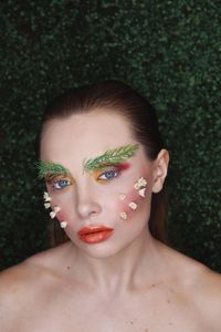 Portrait of beautiful young woman with flower on face outdoors