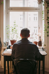 Rear view of businessman sitting on chair at home office