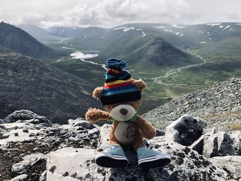 Stuffed toy on rocks against mountains and sky